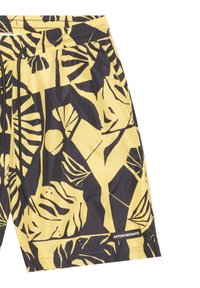 Bañador corto de tela amarilla con estampado de hojas tropicales negras, cinturilla elástica con cordón y etiqueta de marca en el dobladillo.
