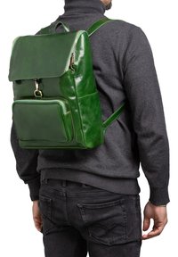 Zaino in pelle verde con design strutturato, tasca frontale e dettagli in oro sulla cerniera. Spallacci regolabili e finitura testurizzata.