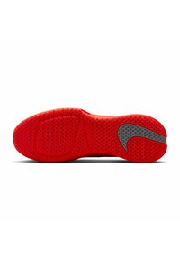 Rote Nike-Schuhsohle mit strukturiertem Grip-Muster und einem grauen Swoosh-Logo in der Nähe der Ferse, vor einem weißen Hintergrund präsentiert.