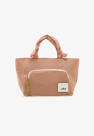 Gran bolso de lona rosa con asas de tela anudadas, un bolsillo frontal con cremallera blanca y una pequeña etiqueta con texto en negro. Textura suave y lisa.