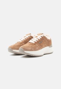 Sneaker in camoscio marrone chiaro con lacci bianchi, foderati in pelliccia e suola testurizzata. Presenta un logo del marchio e dettagli perforati sulla tomaia.