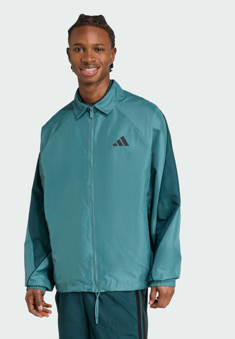 Türkise Windbreaker-Jacke mit Reißverschluss, Stehkragen, elastischen Bündchen und schwarzem Logo auf der Brust. Glattes, leichtes Material.