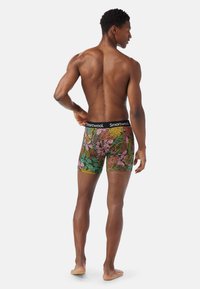 Herrens kalsonger i boxer-modell med ett färgglatt lövmönster, svart elastisk midjeband med "Smartwool"-logotyp, tillverkade av mjukt stretchigt tyg.