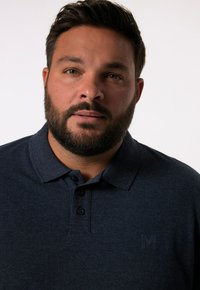 Námořnická modrá polo košile vyrobená z texturované bavlny, s límečkem, třemi knoflíky a diskrétním logem na levém prsu.