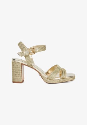 Gold woven strappy sandals with a chunky block heel and a metallic finish. Features adjustable ankle strap with a buckle for secure fit.