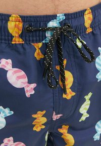 Costumi da bagno colorati con una base blu navy e motivi di caramelle multicolori. Include un cordoncino nero con accenti bianchi.