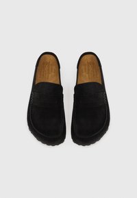 Sorte semskede loafers med en glatt overflate og sømdetaljer. Myke beige innsider gir kontrast og komfort. Rund tå, slip-on design.