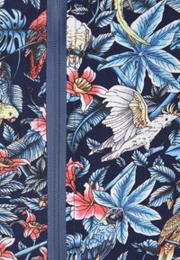 Stampa tropicale con fiori blu e rosa, foglie verdi e uccelli colorati su uno sfondo blu scuro, con un dettaglio centrale della cerniera.