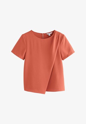 Korallefarbige Bluse mit kurzen Ärmeln und runder Ausschnitt, diagonaler Faltenbeschreibung an der Vorderseite und unsichtbarem Reißverschluss auf der Rückseite. Glatte Stofftextur.