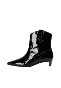 Botines negros brillantes con punta puntiaguda, tachuelas decorativas y tacón bajo; hechos de cuero charol, con un corte elegante.