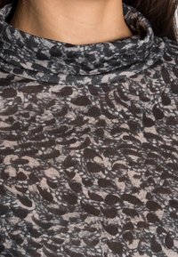Långärmad topp med huva i genomskinligt, lätt material med ett abstrakt mönster i svart och grått samt en smidig yta.