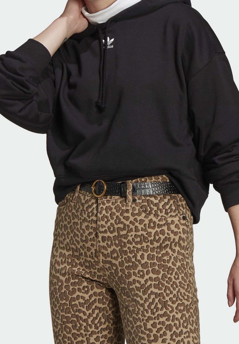 Sudadera negra con cordón y logo blanco, combinada con pantalones de mezclilla de leopardo marrón y un cinturón texturizado negro con hebilla dorada.