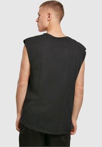 Sort ærmeløs T-shirt med rund halsudskæring og afslappet pasform, fremstillet af blødt bomuldsmateriale og med en let buet kant.