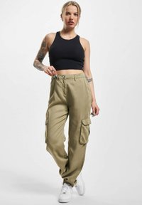 Khaki cargo bukser med sidelommer, lavet af bomuldsblandingsstof. Sammen med en sort ribbet crop top og hvide sneakers.