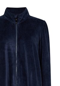 Marinblå sammetjacka med ståkrage, hel dragkedja fram och subtil lyster, med långa ärmar och en avslappnad passform.