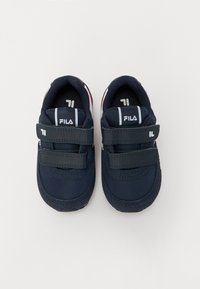 Tummansinisiä lenkkareita, joissa on kaksi tarranauhaa, verkkokangasta ja synteettisiä materiaaleja, pehmustettu sisustus sekä erottuvat valkoiset ja punaiset yksityiskohdat.