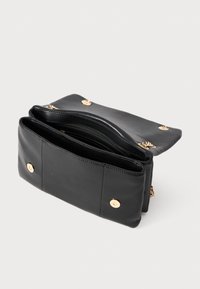 Black leather clutch purse open, showing multiple compartments with gold-tone snap buttons and chain detail on a white background.