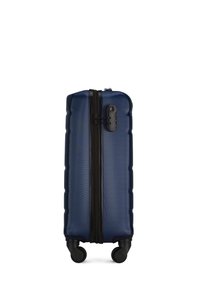 Marineblauwe harde koffer met een gestructureerd oppervlak, zwarte rits en 4 wielen voor mobiliteit. Beschikt over een vergrendelmechanisme aan de zijkant.
