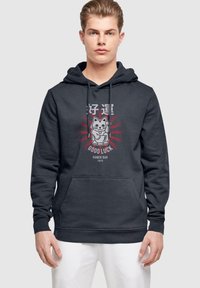 Dunkelgraue Kapuzenjacke mit einer Fronttasche, einer Kordelzugkapuze und einem Grafikdruck eines Katzenmotivs mit roten Strahlen und dem Text "Good Luck Ramen Bar Tokyo."
