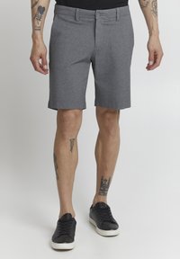 Shorts gris en matériau texturé, avec une coupe droite et deux poches latérales. Associés à des baskets noires pour un look décontracté.