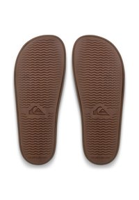 Bruine rubberen binnenzolen voor sandalen met een gestructureerd golvend patroon. Voorzien van een logo vlakbij de hiel en een gladde afwerking voor comfort en grip.