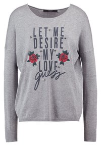 Szary sweter z szerokim dekoltem, z napisem „LET ME DESIRE MY LOVE guess” w ciemnoniebieskim kolorze, ozdobiony grafikami czerwonych róż i dodatkami.