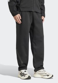 Čierne športové nohavice vyrobené z hladkej, elastickej látky. Majú elastický pás, zúžený strih a reflexný pruh pri leme.