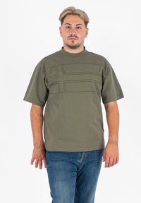 Oliwkowa koszulka z krótkim rękawem z teksturowanym poziomym wzorem na klatce piersiowej, wykonana z miękkiej bawełny.