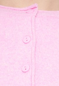 Ροζ ζακέτα με κοντά μανίκια, με απαλή υφή πλεξίματος και τρία κουμπιά στο μπροστινό μέρος, με ευθύ γιακά.