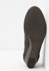 Semelle d'une chaussure Tamaris noire taille 37, montrant le motif de la bande de roulement et le détail antidérapant du talon.