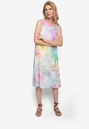 Sukienka bez rękawów w pastelowych kolorach z okrągłym dekoltem, plisami i przewiewnym fasonem; zestawiona z brązowymi sandałami na paski.