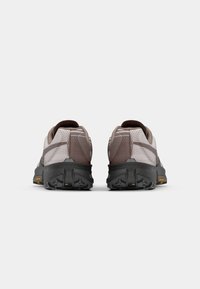 Baskets de sport marron et gris avec un dessus texturé, un col rembourré et des semelles noires robustes arborant un logo Vibram.