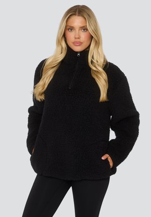 Schwarzer Fleece-Pullover mit hohem Kragen, halbem Reißverschluss und Seitentaschen. Besteht aus einem weichen, strukturierten Stoff und hat eine lockere Passform.