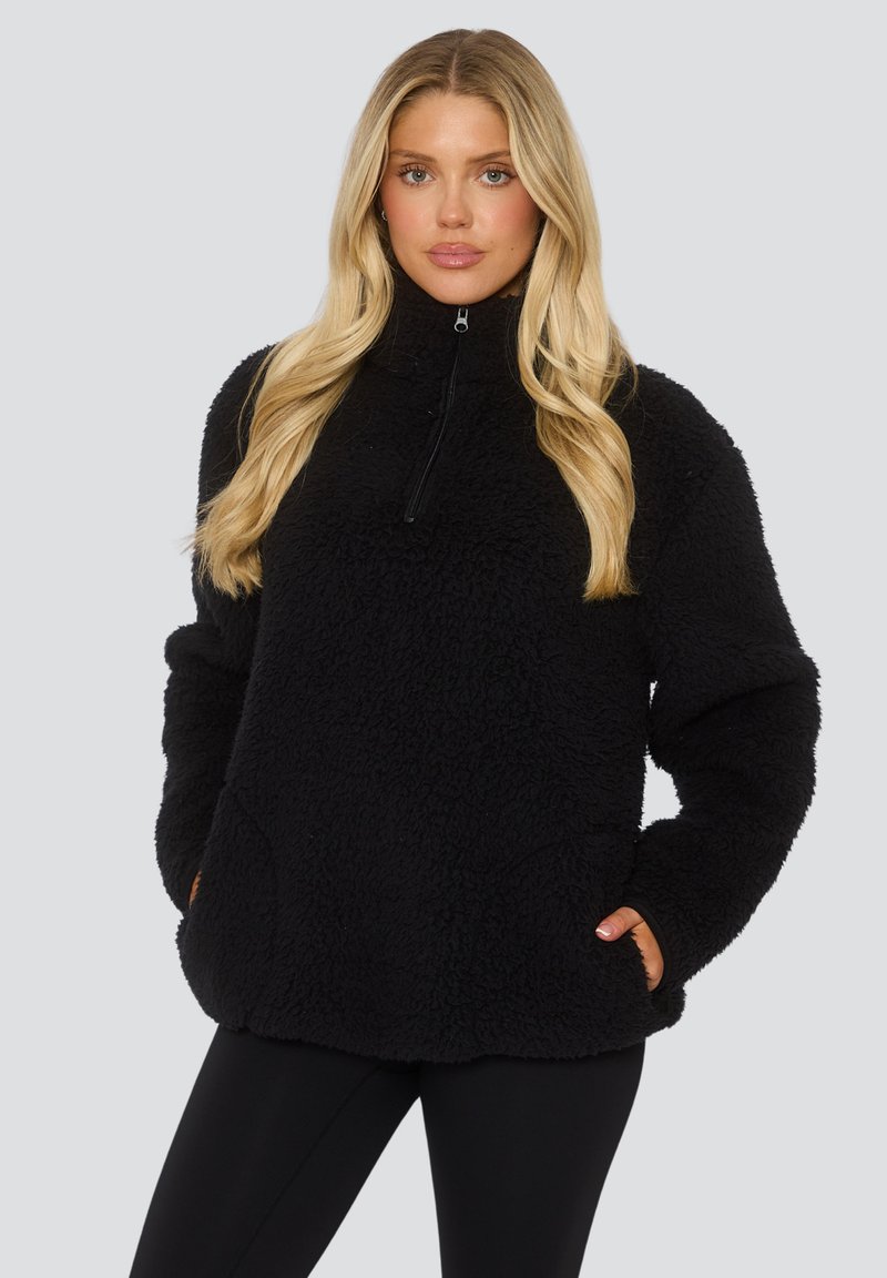 Felpa nera in pile con colletto alto, mezza zip e tasche laterali. Caratterizzata da un tessuto morbido e testurizzato e una vestibilità comoda.