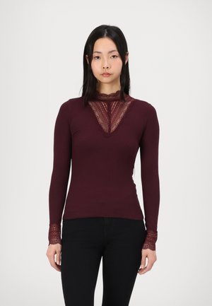 Camiseta de manga larga burdeos con un cuello y puños de encaje, de diseño ajustado y textura acanalada. Sin logotipos ni patrones visibles.