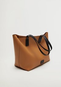 Brązowa skórzana torba tote z teksturowanym wykończeniem, z czarnymi uchwytami i prostokątnym akcentem z przodu. Szeroki i przestronny design.