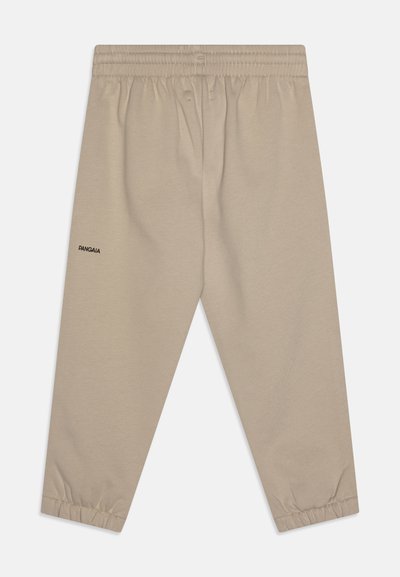 Pantalones de chándal beige con cintura y puños elásticos. Presenta un pequeño logotipo negro en la pierna izquierda. Fabricados con una tela suave y texturada.