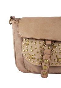Borsa in pelle beige con pattina ripiegata, caratterizzata da borchie dorate e un anello circolare. Superficie texturizzata con una finitura liscia.