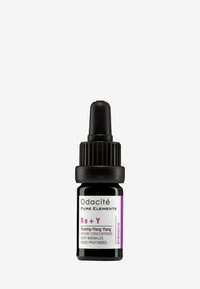 Odacité Rō + Y Ylang Ylang-serum i en svart glasdroppflaska. Har ett ribbat svart lock och en vit etikett med lila accenter.