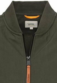 Olijfgroene bomberjack met rits aan de voorkant, ribbelkraag en leren accent op de rits; de stof lijkt glad met een matte afwerking.