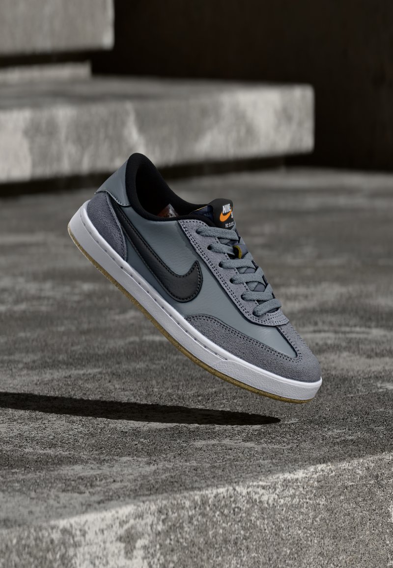 Nike-sneaker i grått skinn og semsket skinn med en svart swoosh, hvit mellomsåle og teksturert gummiyttersåle med gum-detaljer.