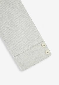 Cuff in tessuto grigio a righe con una superficie liscia, dotato di due bottoni color crema per la chiusura. Design semplice e funzionale.