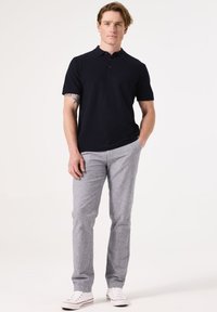 Navy korte mouw polo met een textuurstof, gecombineerd met lichtgrijze, op maat gemaakte broek en witte sneakers, voor een casual uitstraling.