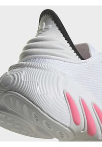Athletic shoe with a textured white upper, black accent at the collar, and a rubber sole featuring prominent pink accents.