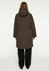 Mørkebrun parka med hætte, justerbar talje, lange ærmer og sidelommer, lavet af et glat, let materiale.