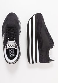 Czarne trampki z zamszowej i tekstylnej cholewki, płaskie sznurówki, platforma z białymi paskami oraz etykieta w szachownicę na języku.