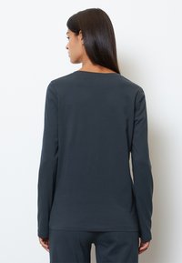 Langärmliges Oberteil in Dunkelgrau, aus weichem Stoff gefertigt. Verfügt über einen runden Halsausschnitt, enganliegende Ärmel und einen geraden Schnitt am Saum.
