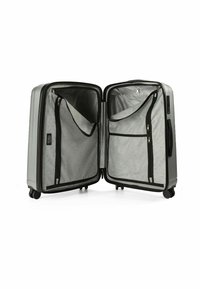 Silberner Hartschalenkoffer mit zwei Fächern, Nylon-Netz Taschen, Reißverschlüssen und vier Rollen für Mobilität. Das Innere ist mit einem hellgrauen Futter ausgestattet.