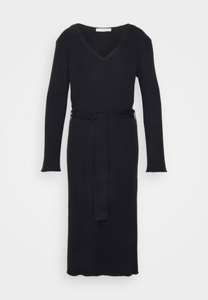 Sort ribstrikket kjole med V-udskæring, lange ærmer og et matchende bælte. Har en lige silhuet og en bølget kant.