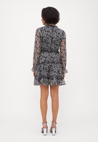 Svart og kremfarget kjole med paisley-mønster, lange gjennomsiktige ermer, volangnederste og innsvinget midje. Brukt med strappy hvite blokkhæl sandaler.